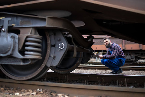 Trabalhador ferroviário inspecionando rodas e freios do trem de carga